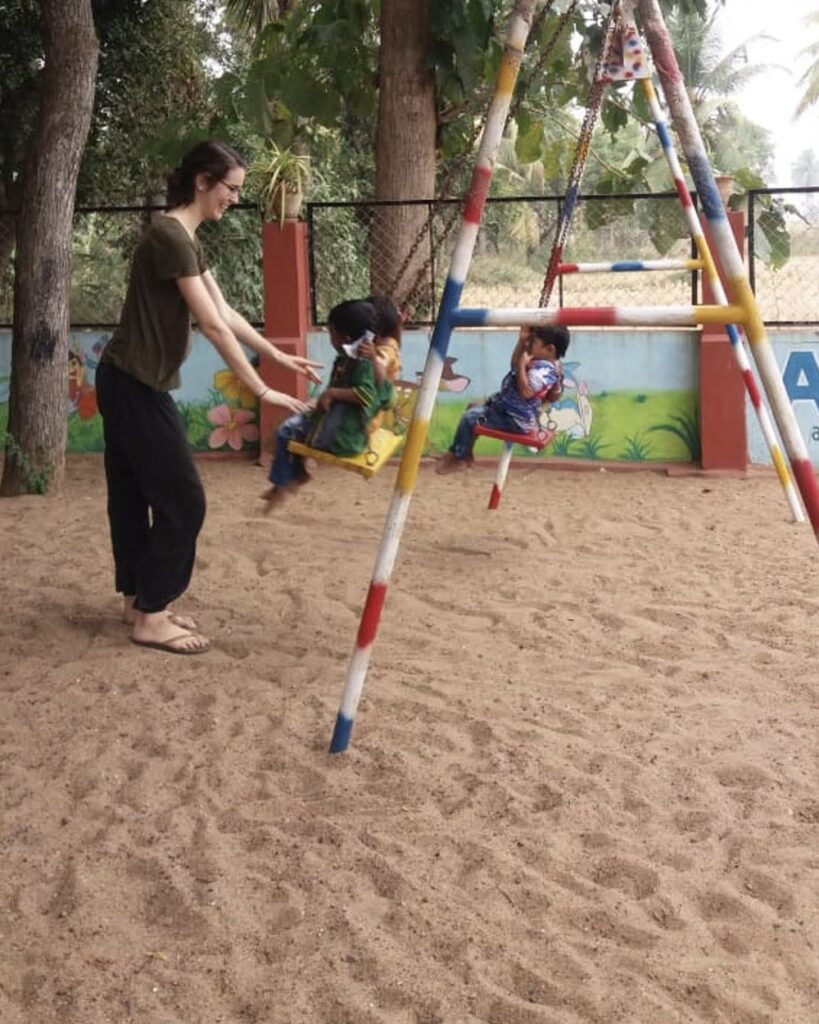 Eine Volontärin spielt mit Kindern auf einer Schaukel